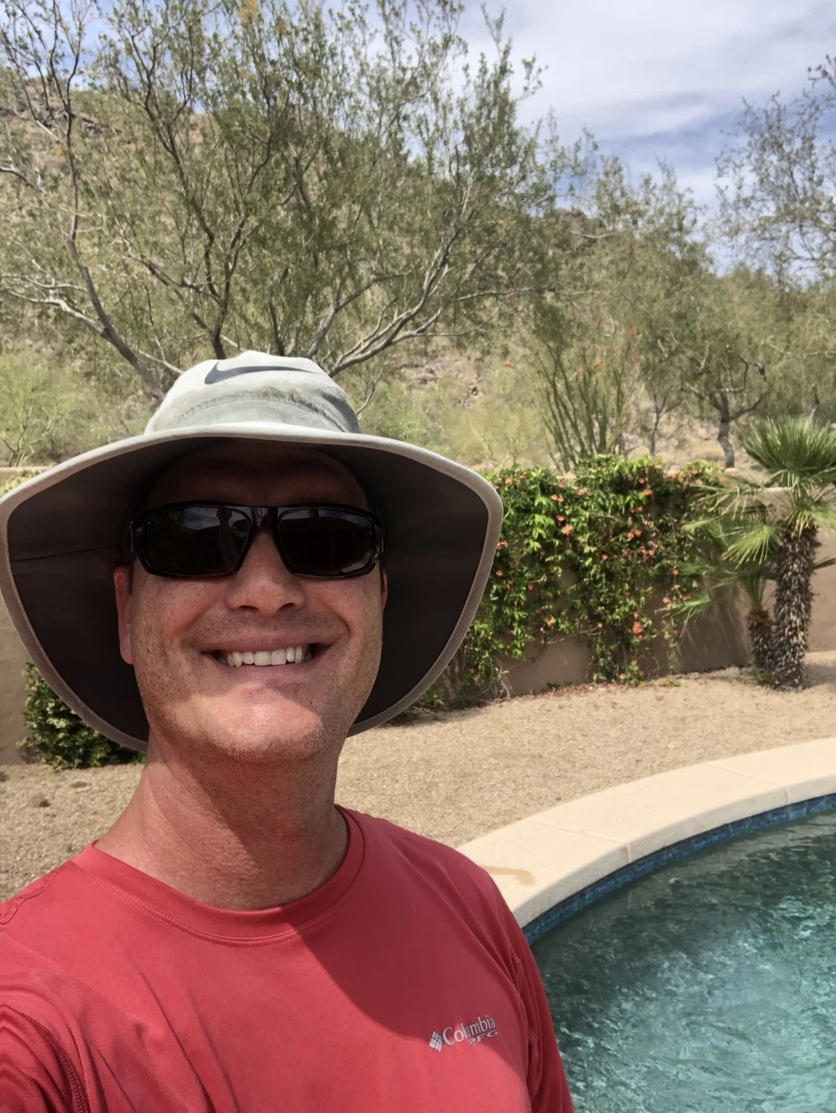 Ethan Eckburg poolside in Phoenix — sun hat, sunglasses and a service shirt, on the job